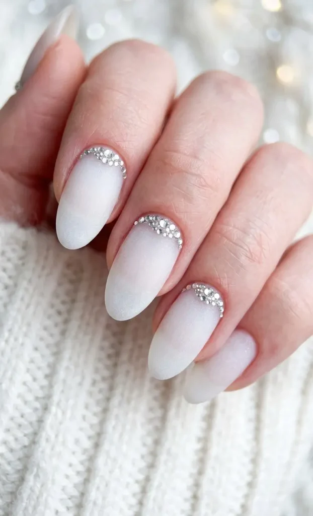 Frosted White Almond Nails With Silver Rhinestone Cuticle Crescent