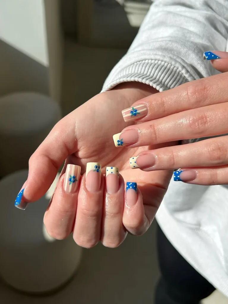 Cool girl nail designs with mix and match French tips featuring blueberries, cream stripes, and blue dots on short square nails