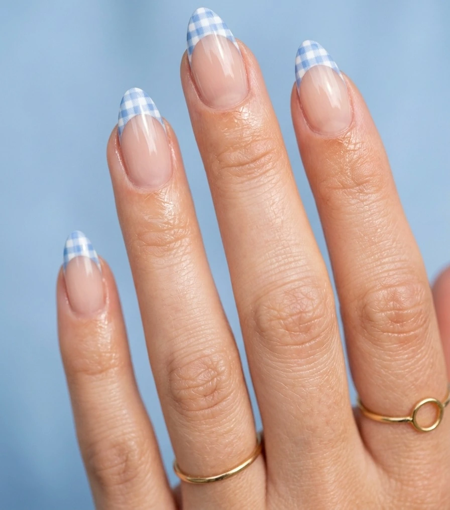 Cool girl nail designs with a nude base and soft blue gingham check French tips on almond nails