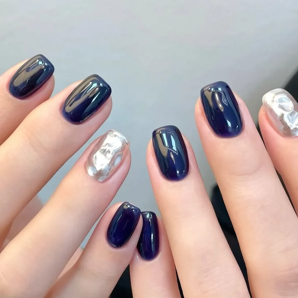 Cool girl nail designs in glassy deep navy with a molten silver chrome accent nail on short square nails