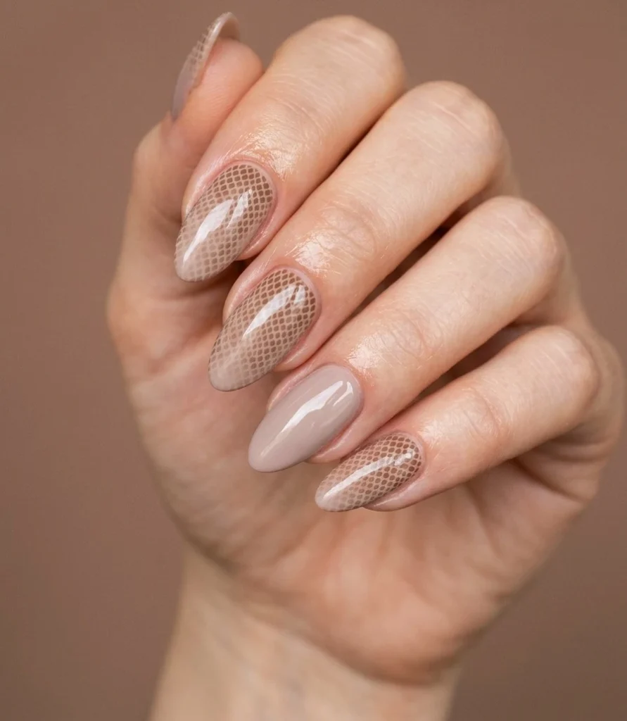 Cool girl nail designs with a taupe base and fine warm brown snake skin print with nude accent nails on almond nails
