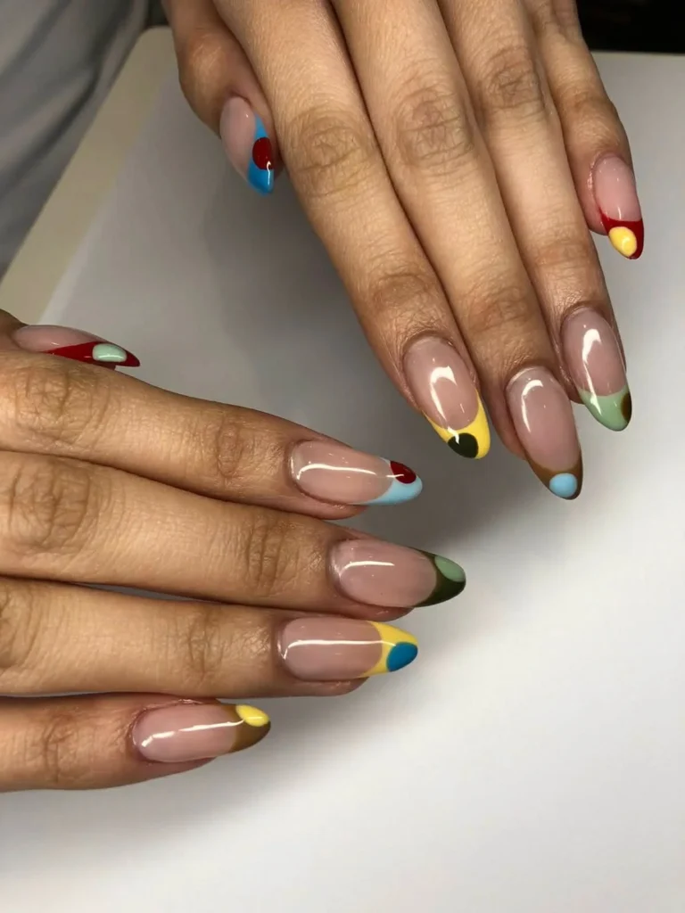 Cool girl nail designs with bare nude base and two tone abstract French tips in primary colors with a dot accent on long almond nails