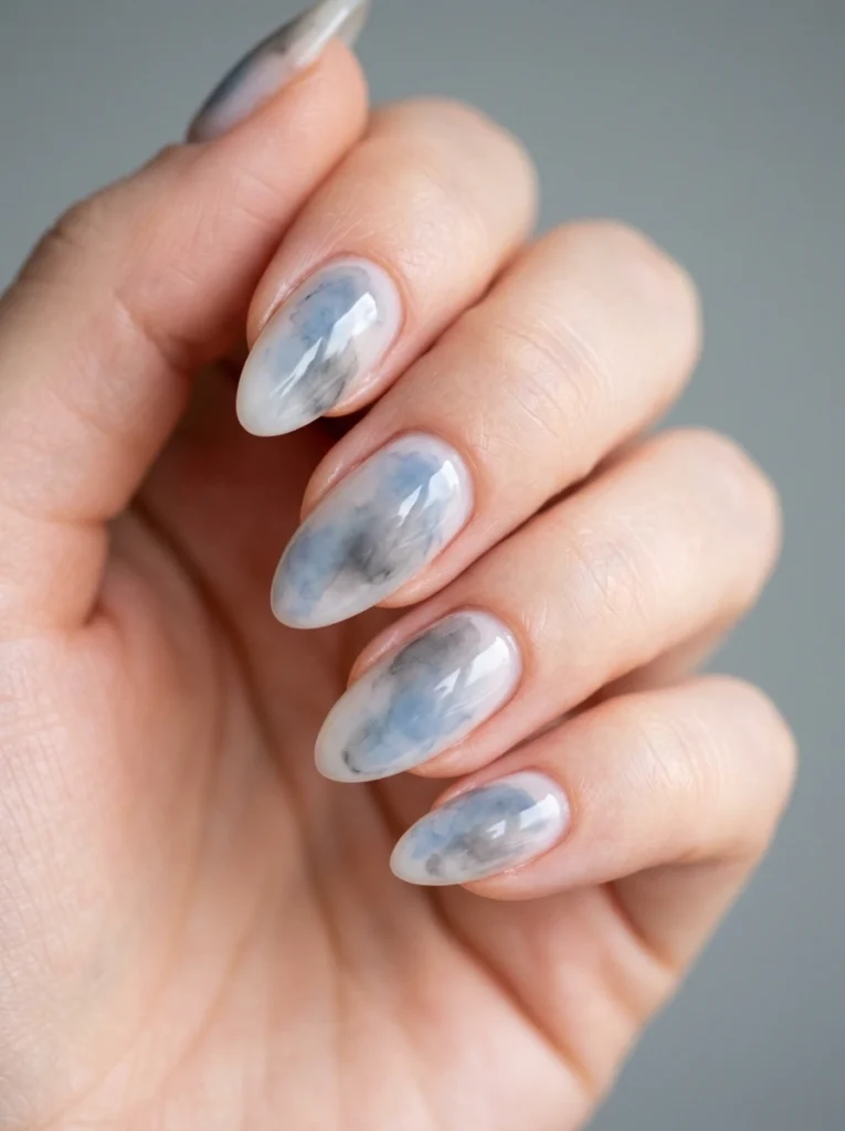 Cool girl nail designs with a soft watercolor wash of muted blue and grey on almond nails
