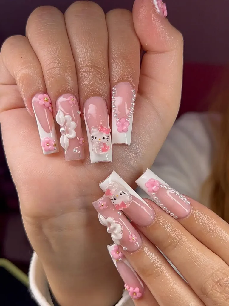 Long coffin Hello Kitty nails with 3D Kitty faces, raised pink and white flowers, pearls, and white French edges on a clear pink base