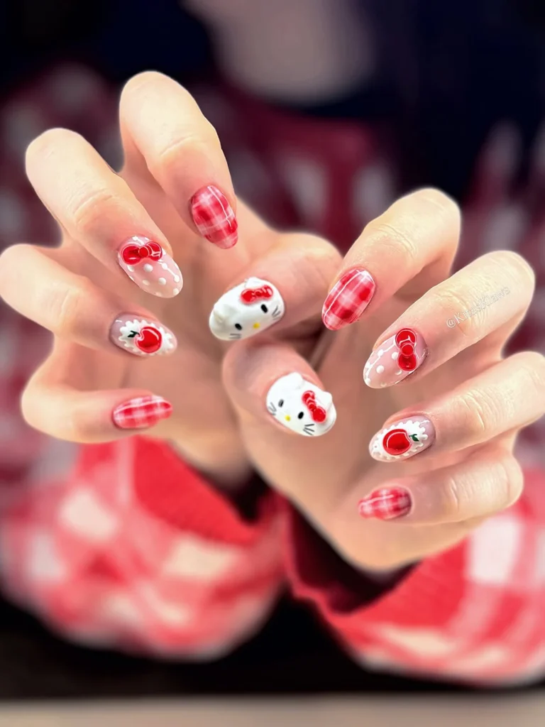 Cottagecore red gingham Hello Kitty nails with 3D Kitty faces, red bows, cherries, white lace, and polka dots on short almond nails