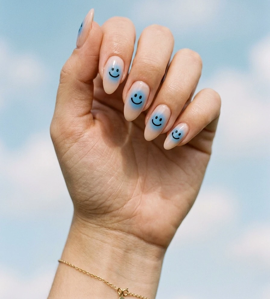 Summer smiley face nails with soft blue aura glow and small black smiley faces on medium almond nails