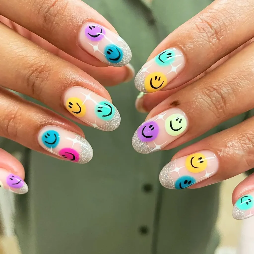 Summer smiley face nails with silver glitter French tips and paired colorful smiley faces on long almond nails