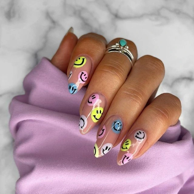 Summer smiley face nails with multicolor melty smiley faces on long nude almond nails
